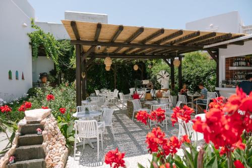 a patio with tables and chairs and red flowers at Eleni Rooms in Parikia