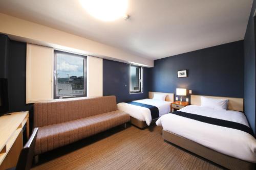 a hotel room with two beds and a couch at Country Hotel Takayama in Takayama