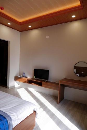 a bedroom with a bed and a tv on a wall at Diamond Luxury Hotel & Café Măng Đen in Kon Plong