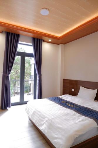 a bedroom with a bed and a large window at Diamond Luxury Hotel & Café Măng Đen in Kon Plong