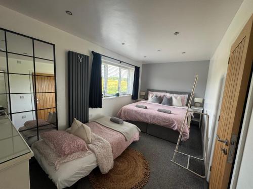 a bedroom with two beds and a mirror at Abbey’s Inn in Cheadle