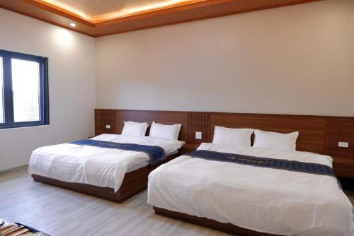 a bedroom with two beds and a window at Diamond Luxury Hotel & Café Măng Đen in Kon Plong