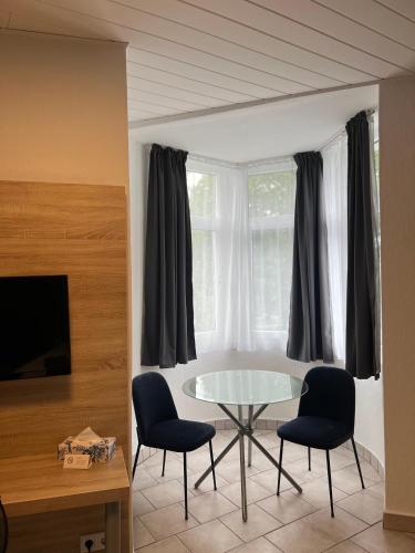 a living room with a glass table and two chairs at Hotel Monopol in Hilden