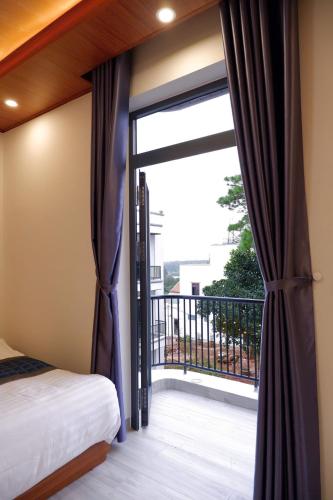 a bedroom with a sliding glass door to a balcony at Diamond Luxury Hotel & Café Măng Đen in Kon Plong