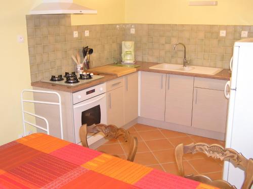 a kitchen with a stove and a sink and a table at Maison de caractère à Roscoff in Roscoff