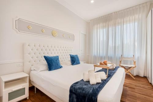 a white bedroom with a large bed with blue pillows at GOLDEN LUXE - Seafront Terrace next to the Beach in Marina di Pietrasanta
