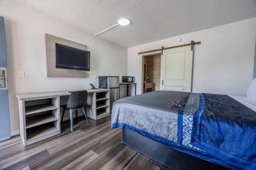 a bedroom with a bed and a desk and a tv at Oyo Hotel Bartow in Bartow