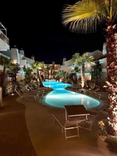 a resort pool with chairs and palm trees at night at Luxury Beach and Pool House Jesolo in Lido di Jesolo