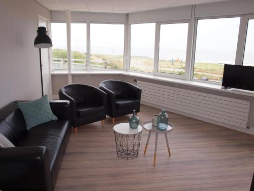 a living room with a couch and two chairs and a tv at Residence Le Mistral in Noordwijk aan Zee