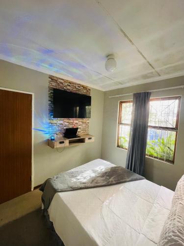 a bedroom with a bed and a tv on the wall at Lala Properties in Bloemfontein