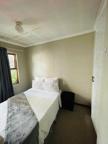 a bedroom with a bed with white sheets and pillows at Lala Properties in Bloemfontein