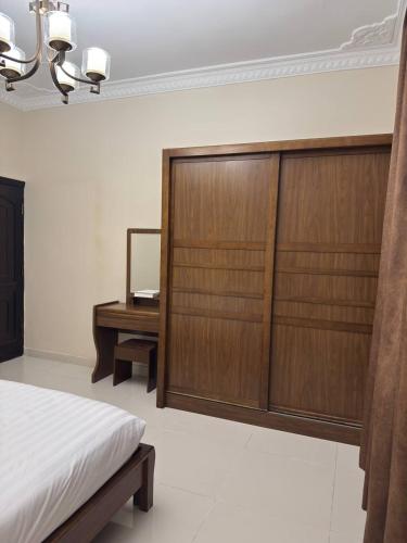 a bedroom with a bed and a wooden closet and a desk at سحاب الأندلس للشقق المخدومة 1 الوجه Sahab Al Andalus for Served Apartments in Al Wajh