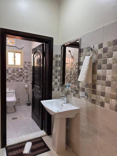 a bathroom with a sink and a toilet and a mirror at سحاب الأندلس للشقق المخدومة 1 الوجه Sahab Al Andalus for Served Apartments in Al Wajh