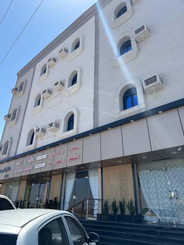 a white building with a car parked in front of it at سحاب الأندلس للشقق المخدومة 1 الوجه Sahab Al Andalus for Served Apartments in Al Wajh