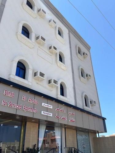 a white building with signs on the side of it at سحاب الأندلس للشقق المخدومة 1 الوجه Sahab Al Andalus for Served Apartments in Al Wajh