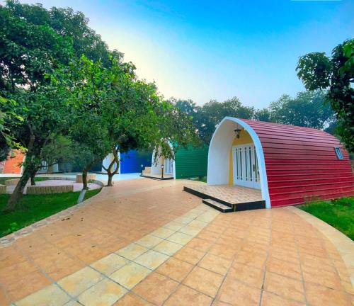 a small house with a red and white roof at Rass Resort Gazipur in Gazipur