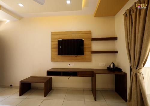 a room with a desk with a television on the wall at Lotus Hotel & Resort in Ambernath