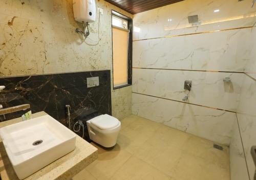 a bathroom with a white toilet and a sink at Lotus Hotel & Resort in Ambernath