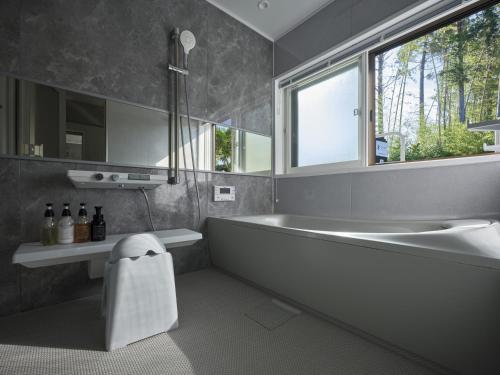 a bathroom with a tub and a sink and a window at 佐渡古民家ステイ さどまり 大和の家 in Sado