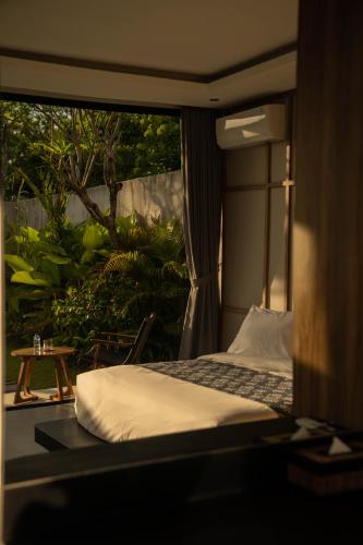 a bed in a room with a view of a garden at The Placo Villa Uluwatu in Denpasar