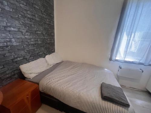 a small bed in a room with a brick wall at East Suite in London