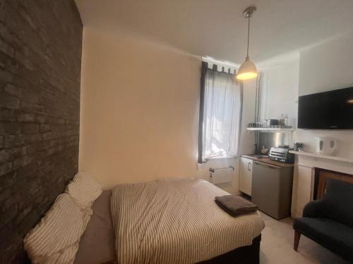a small room with a bed and a kitchen at East Suite in London