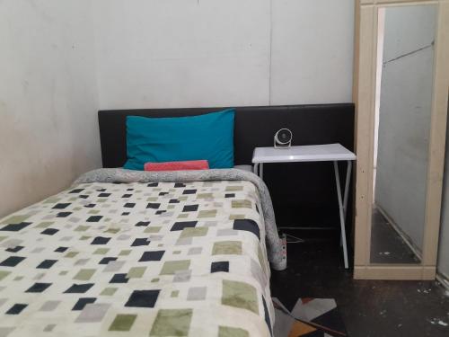 a bedroom with a bed with a blue pillow and a table at 160 West Pietermaritzburg Sanethub in Pietermaritzburg