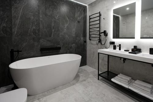 a bathroom with a large white tub and a sink at Glacier Premium Apartments in Bukovel