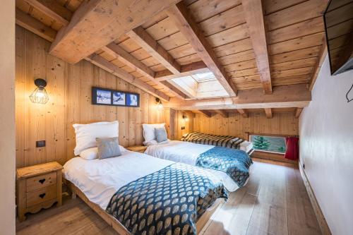 due letti in una stanza con pareti in legno di Chalet Vithos - Luxe, ski aux pieds a Les Bruyères