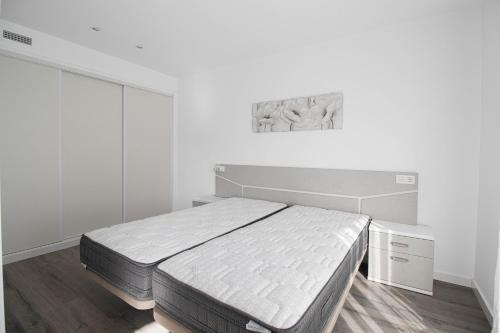 een witte slaapkamer met een bed en een schilderij aan de muur bij Isea 2 in Calpe