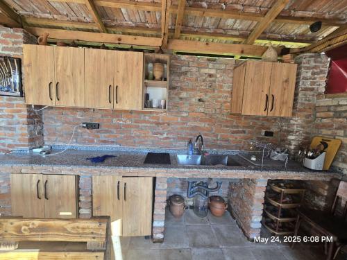 a kitchen with wooden cabinets and a brick wall at Lili's Riverside Villa in Dagva in Zeda Dagva