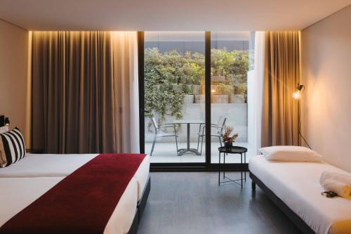 a hotel room with two beds and a balcony at Timbre Boavista in Porto