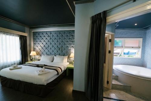 a bedroom with a bed and a bath tub at La Seine City Resort, Chiang Mai in Chiang Mai