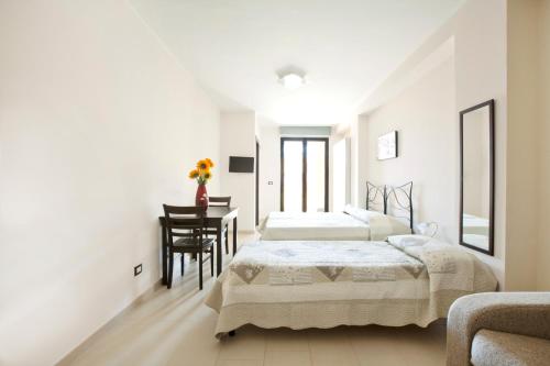 two beds in a white room with a table and chairs at Hotel San Martino in Cassibile