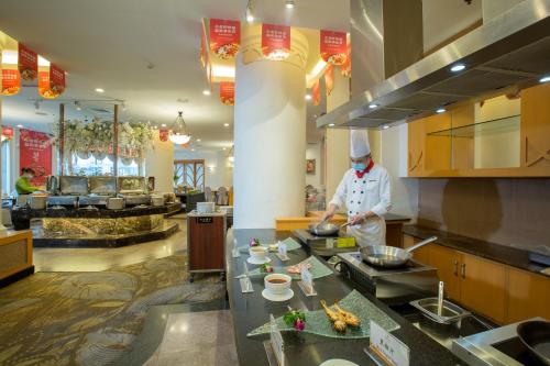 a chef preparing food in a restaurant kitchen at Grand Sun City Hotel-Located city center Metro Access in Changsha