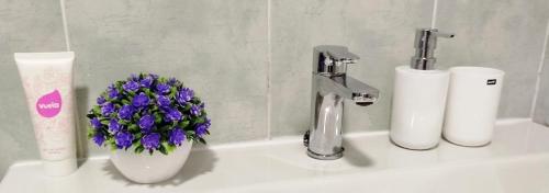 a bathroom sink with a vase of purple flowers on it at Casa Indalo Mojácar in Mojácar