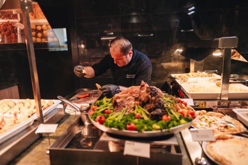a man standing in a kitchen preparing food at Santé SPA Hotel in Velingrad