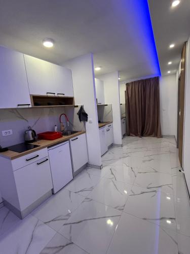 a kitchen with white cabinets and a large tile floor at Apartmani Venecia in Prozor