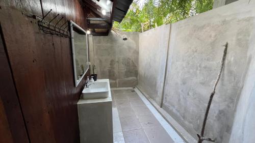 a bathroom with a sink and a concrete wall at Tahlia's Villa in Sorongjukung