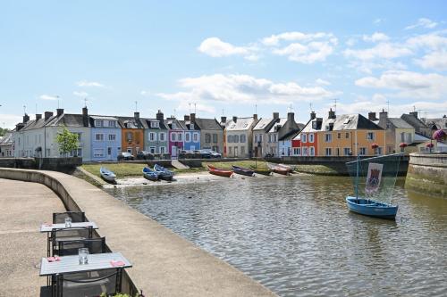 a group of boats in a river with houses at A Fleur de Quai - Vue sur le port in Isigny-sur-Mer