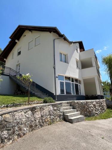 a large white house with a stone wall at Apartmani Venecia in Prozor