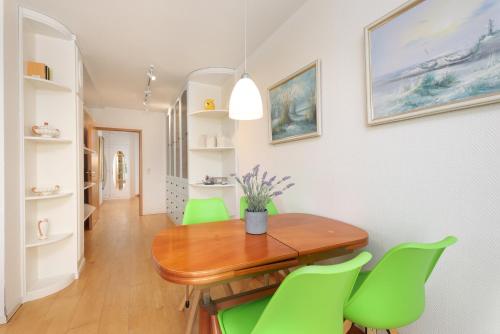 a dining room with a wooden table and green chairs at Villa Fördestrand Spinnaker in Laboe
