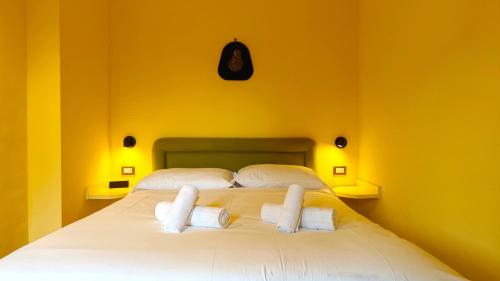 a bedroom with a large white bed with yellow walls at Hostdomus - Alpine Suite in San Sicario