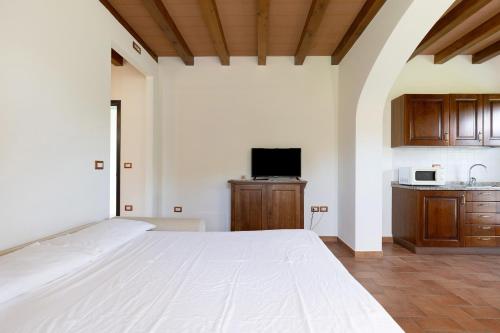 a bedroom with a large white bed and a kitchen at La Bettola Tavern Rooms Restaurant in Montopoli in Val dʼArno
