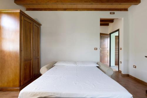 a bedroom with a large white bed with a wooden cabinet at La Bettola Tavern Rooms Restaurant in Montopoli in Val dʼArno