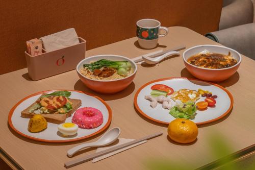 a table with plates of food and bowls of food at Orange Hotel Beijing Daxing International Airport Terminal in Beijing