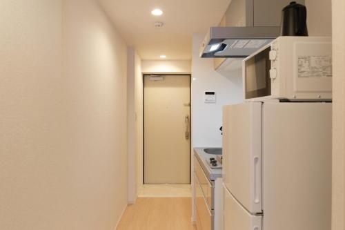 a kitchen with a white refrigerator and a door at J-ARC Akebonobashi in Tokyo