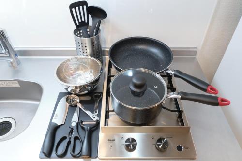 a kitchen counter with pots and pans on a stove at J-ARC Akebonobashi in Tokyo