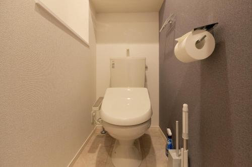 a white toilet in a bathroom with a roll of toilet paper at J-ARC Akebonobashi in Tokyo