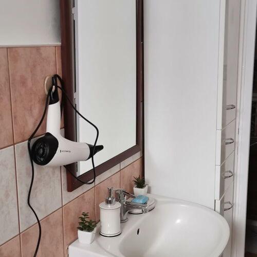a bathroom sink with a hair dryer on a mirror at Szökőkút vendégszállás in Sátoraljaújhely